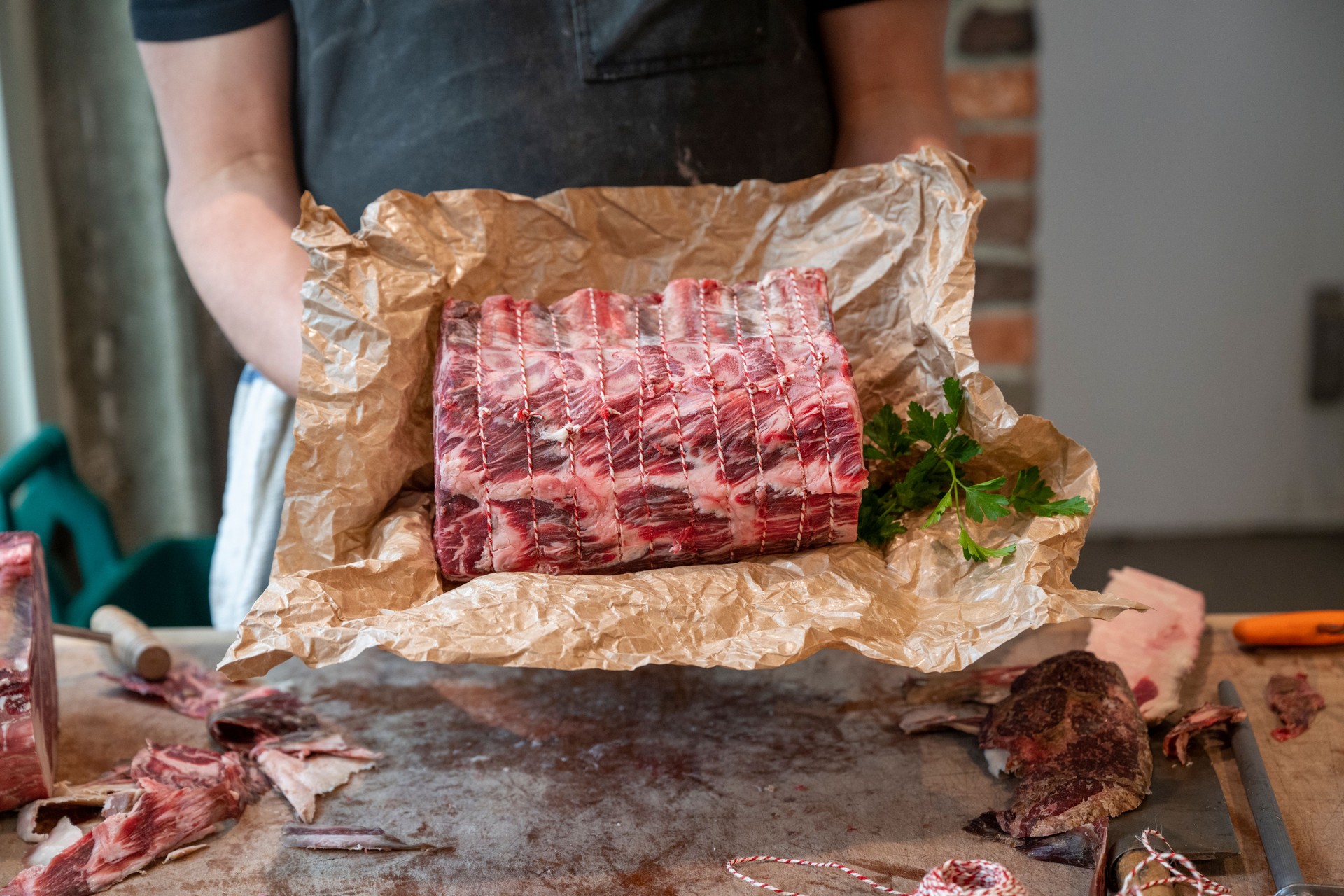 Butcher holds raw beef roast on paper