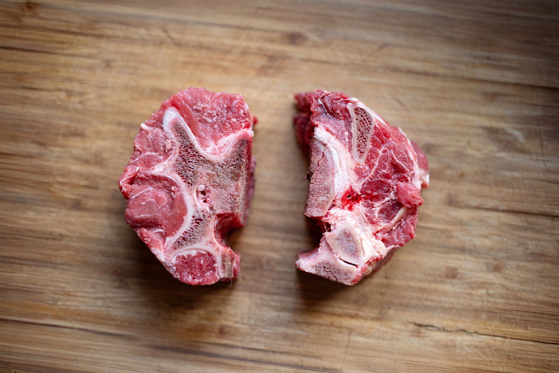 Raw beef neck bone meat on a wooden cutting board. Close up shot, no people