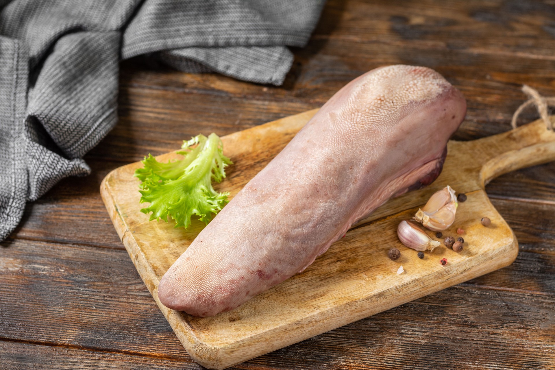 Beef tongue on a wooden Board on a brown wooden table. Raw beef tongue on the kitchen table. Rustic style